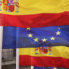 Imagen de las banderas de España y la Unión Europea con la sede del Ministerio de Asuntos Exteriores, de la Unión Europea y Cooperación al fondo