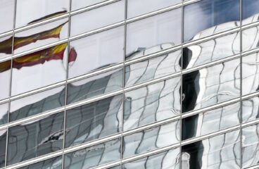 Spanish flag reflected in the windows of a building in the Cuatro Torres Business Area in Madrid (Spain)
