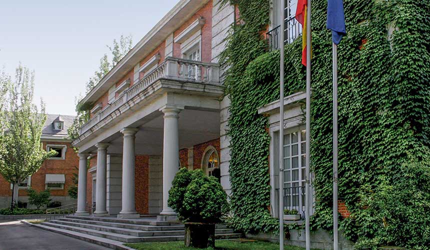 Diagonal view of the façade of the Council of Ministers Pavilion in the Moncloa Complex, with the Spanish and EU flagpoles. Challenges