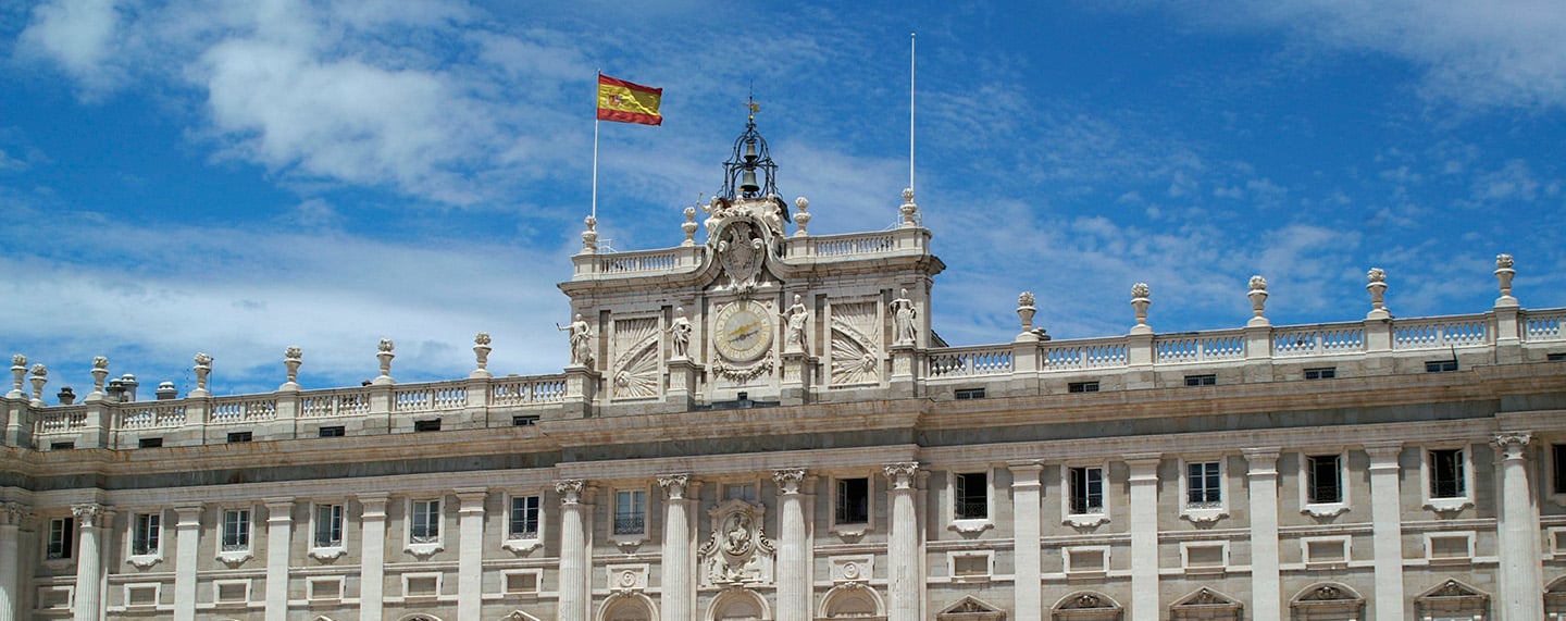 Detail of the façade of the Royal Palace in Madrid with the Spanish flag. King Felipe VI