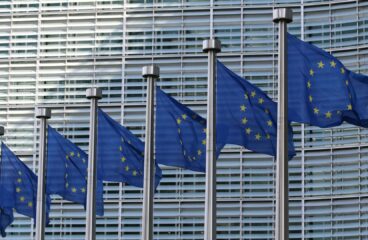 Seven flags of the European Union, with blue background and yellow stars, flying in front of the European Commission headquarters in Brussels (Belgium) during the day. Middle East